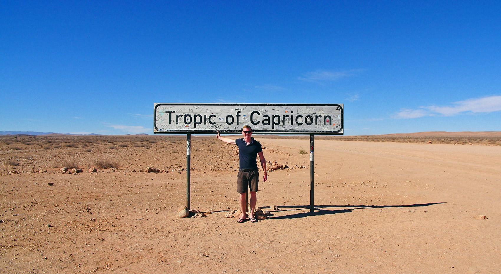 Man in front of sign Tropic of Capricorn Man in front of sign Tropic of Capricorn