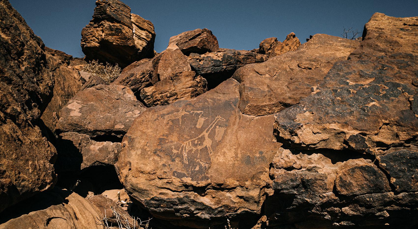 Giraffe und zwei Füße als Felsgravur in Twyfelfontein