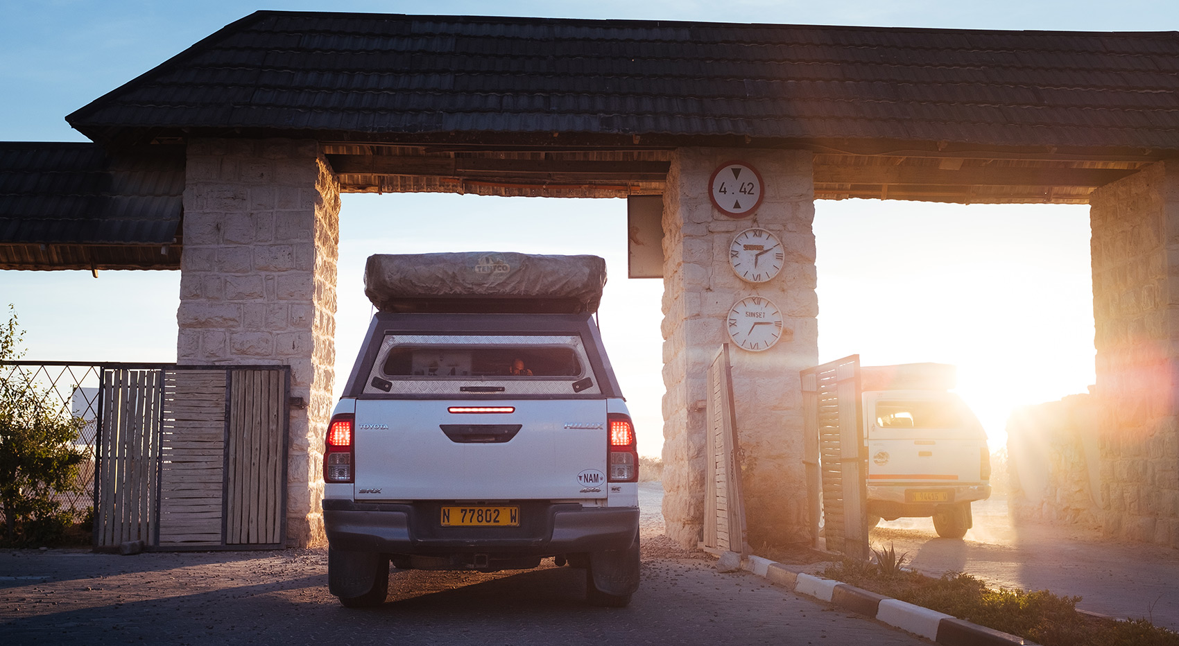 Self-drive vehicle driving through the gate of the Etosha National Park at sunrise.