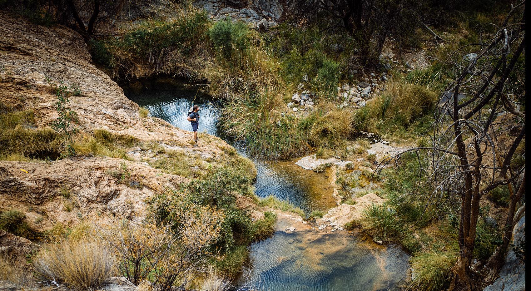 A hike through the Naukluft National Park. A man stands on the rock by the river . A hike through the Namib Naukluft National Park. A man stands on the rock by the river .