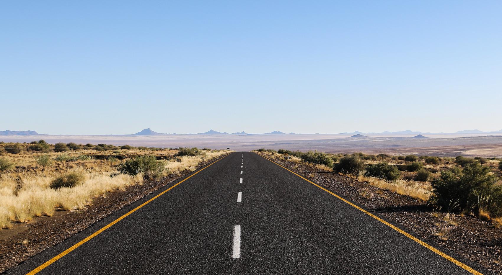A tarmac road leads through the dry Namibian landscape. A tarmac road leads through the dry Namibian landscape.