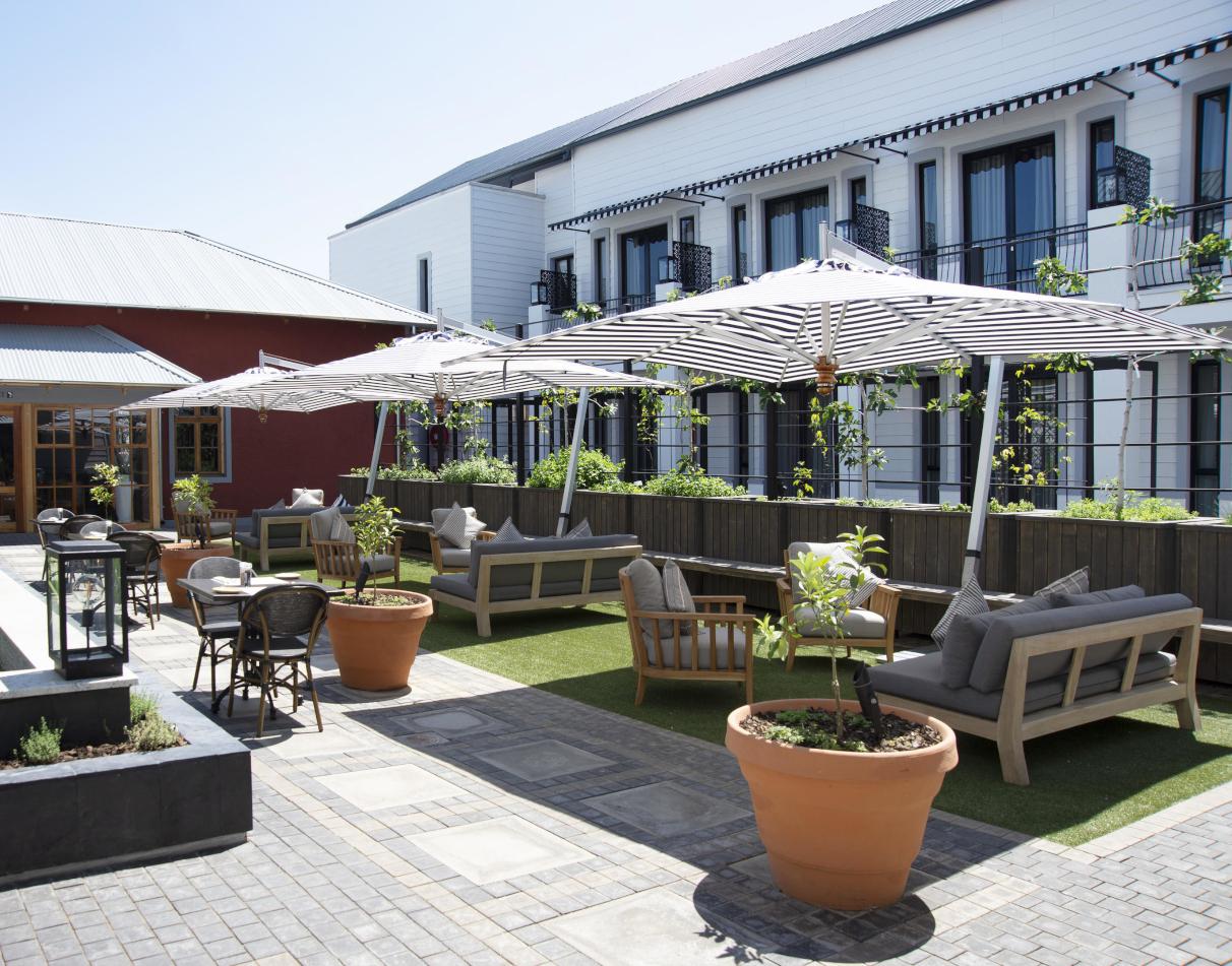 A photo showing the exterior of The Weinberg Hotel in Windhoek, Namibia, featuring a garden table and chairs shaded by umbrellas.