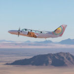 A light aircraft soaring above stunning desert scenery in Namibia.