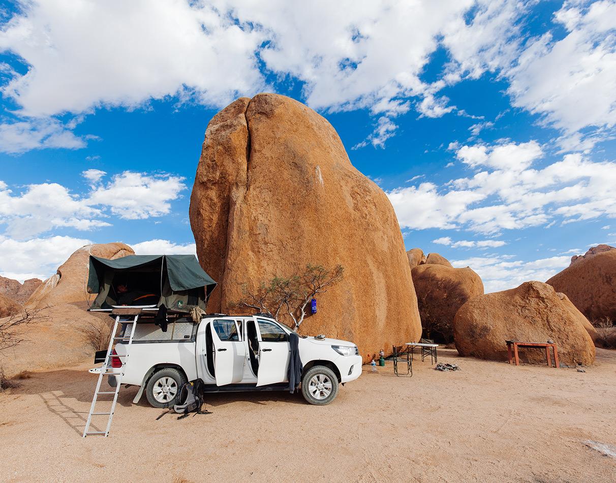 Ein Mietwagen mit Dachzelt, der auf einem Campingplatz in Namibia geparkt ist.