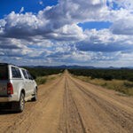 Ein 4x4 Mietwagen steht geparkt am Straßenrand einer geraden Straße, die zum Horizont führt.