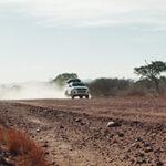 Ein 4x4-Mietwagen fährt auf einer staubigen Schotterstraße.