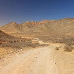 Eine Straße im Richtersveld Nationalpark mit einer Bergkette im Hintergrund.