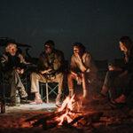 Eine Gruppe von Reisenden, die nachts um ein Lagerfeuer sitzt.