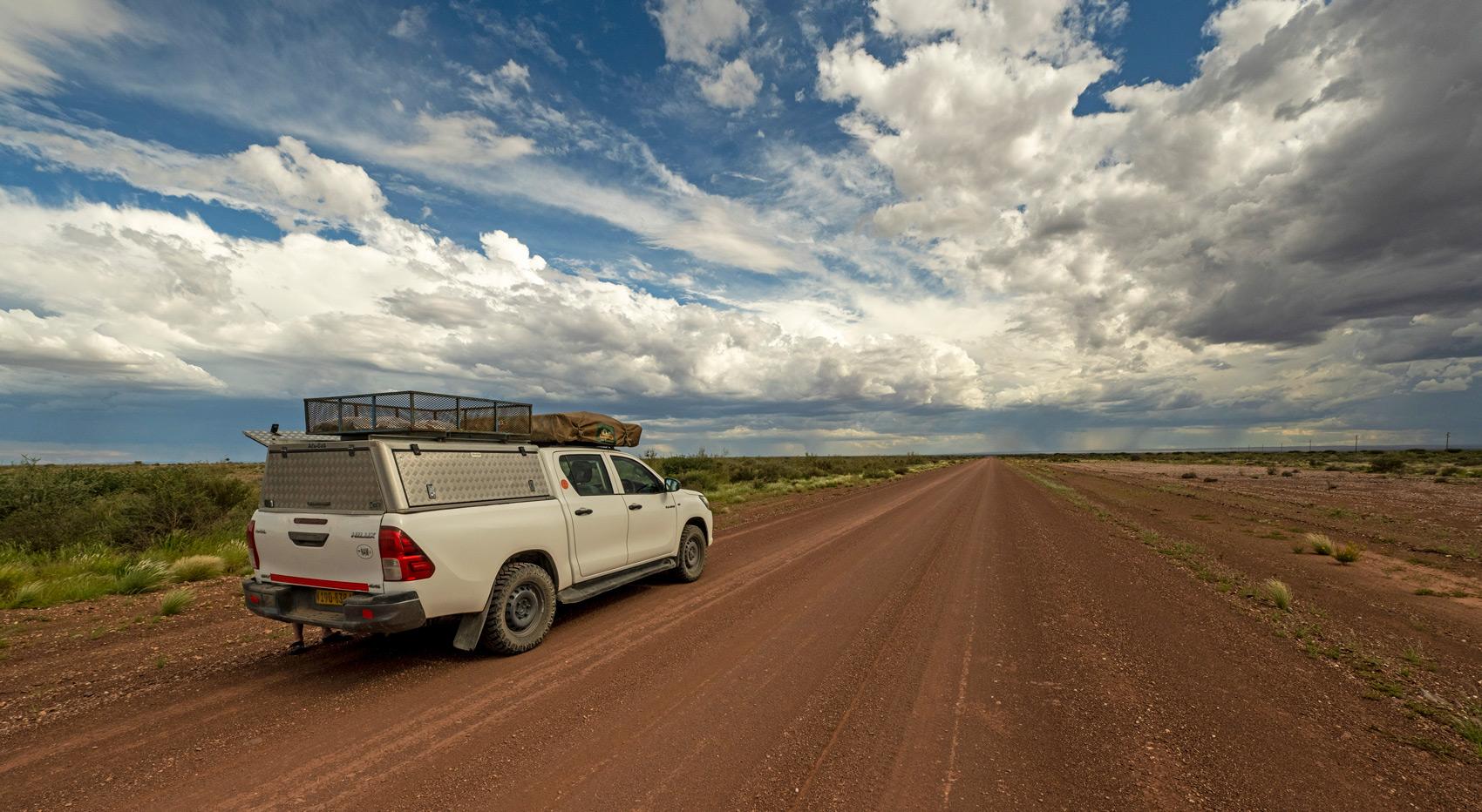 A self-drive vehicle driving on a dirt road in Namibia.
