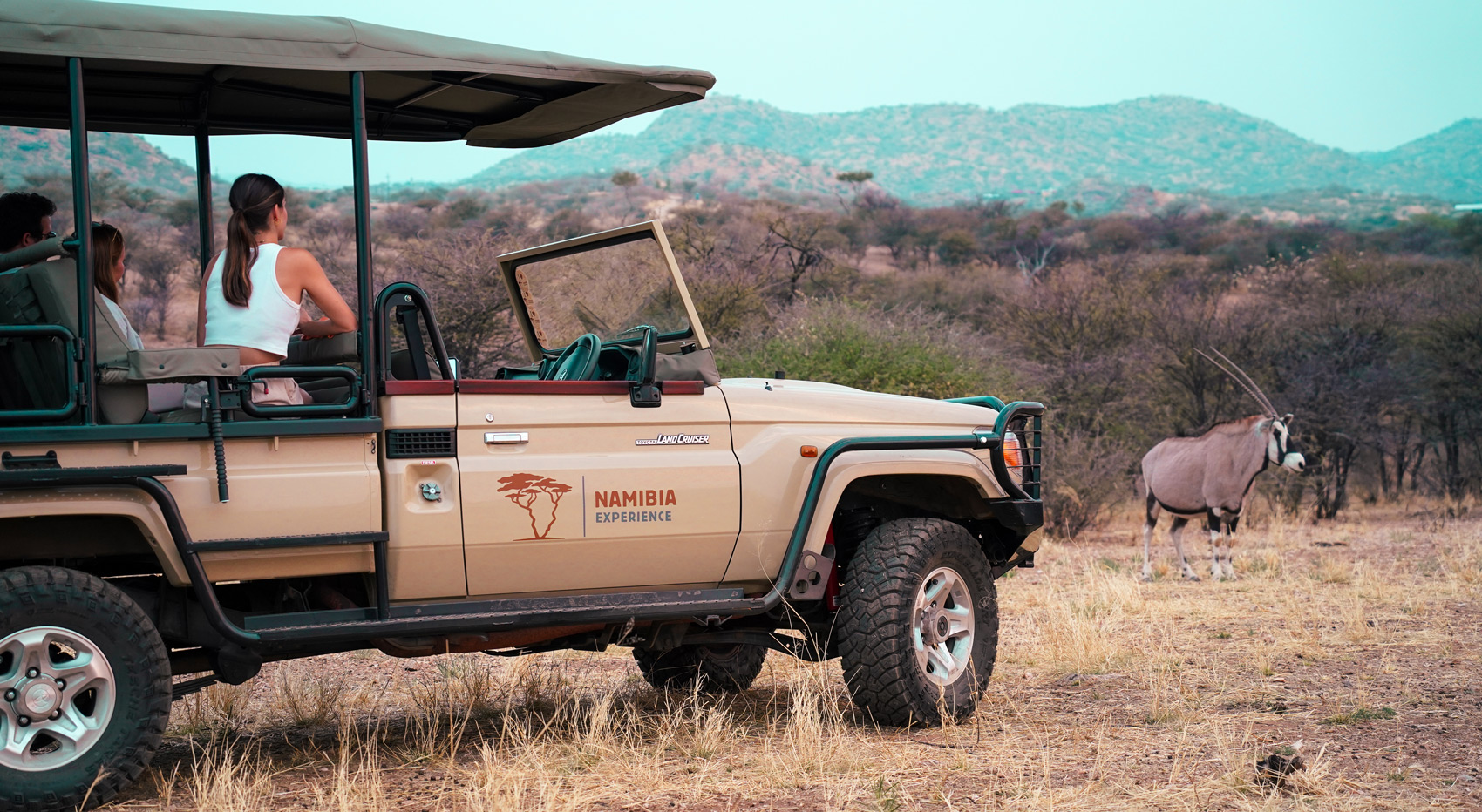 A photo of guests in an open game viewer looking at an oryx in Etosha, Namibia. 