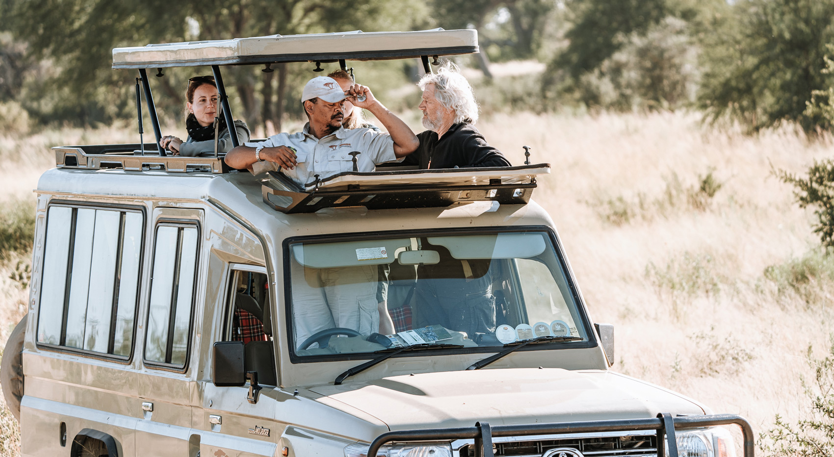 A game drive vehicle with guests and guide looking out of the pop-up roof.