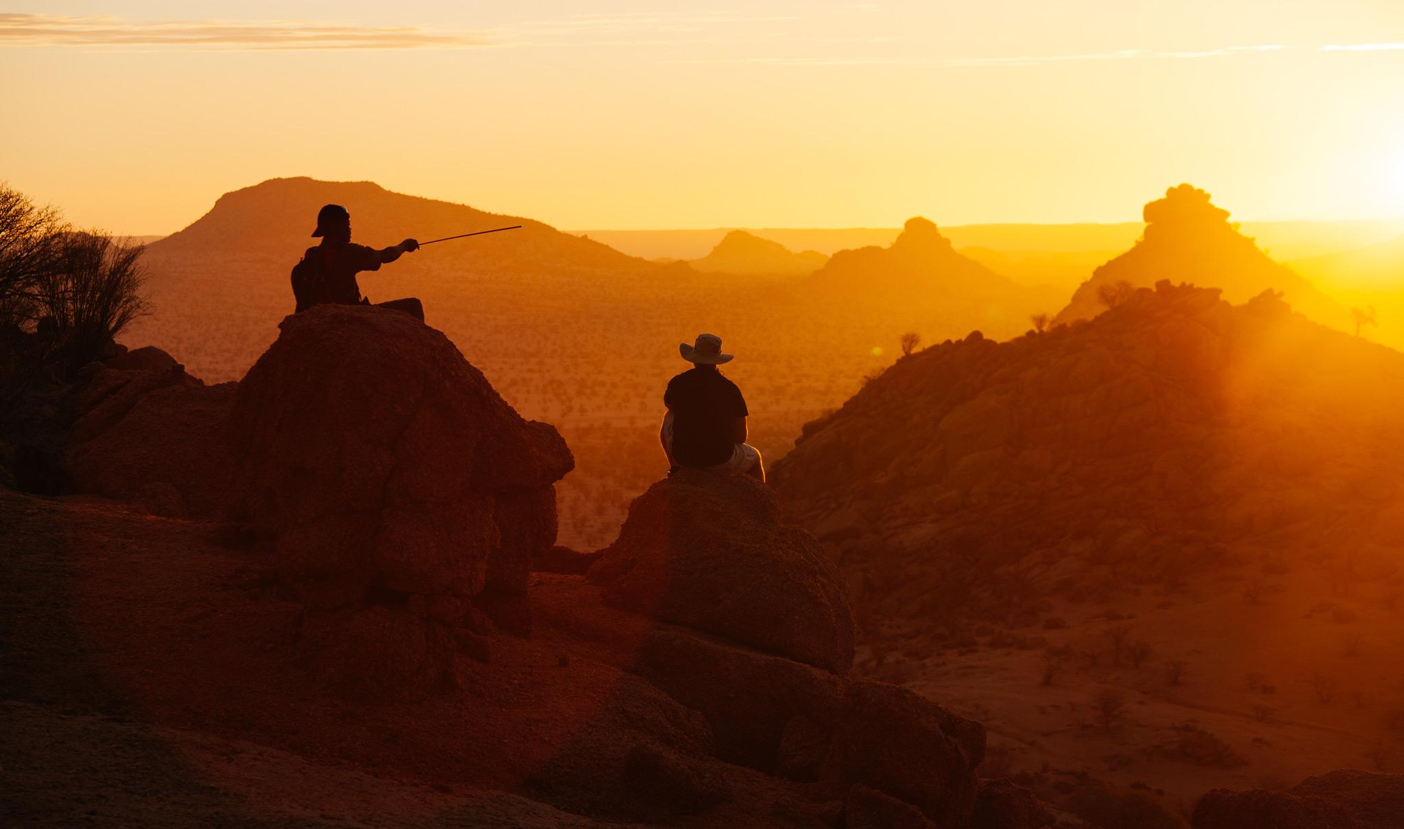 Wanderer in Namibia, die eine Pause einlegen und den Sonnenuntergang auf sich wirken lassen.