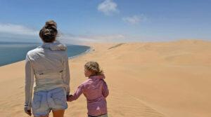 A mother and daughter standing on the beach together in swakopmund.