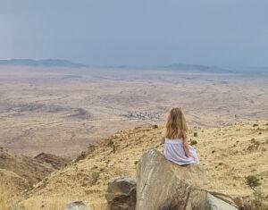 A child on a rock overlooking the namib desert.