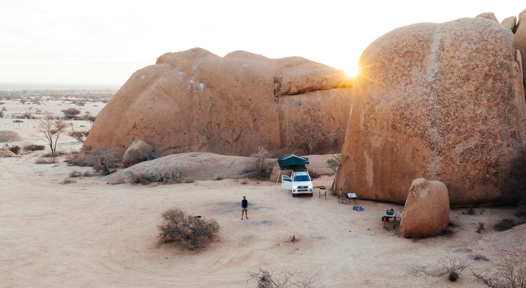 A guest standing amongst the boulders of Spitzkoppe where he has set up camp. 