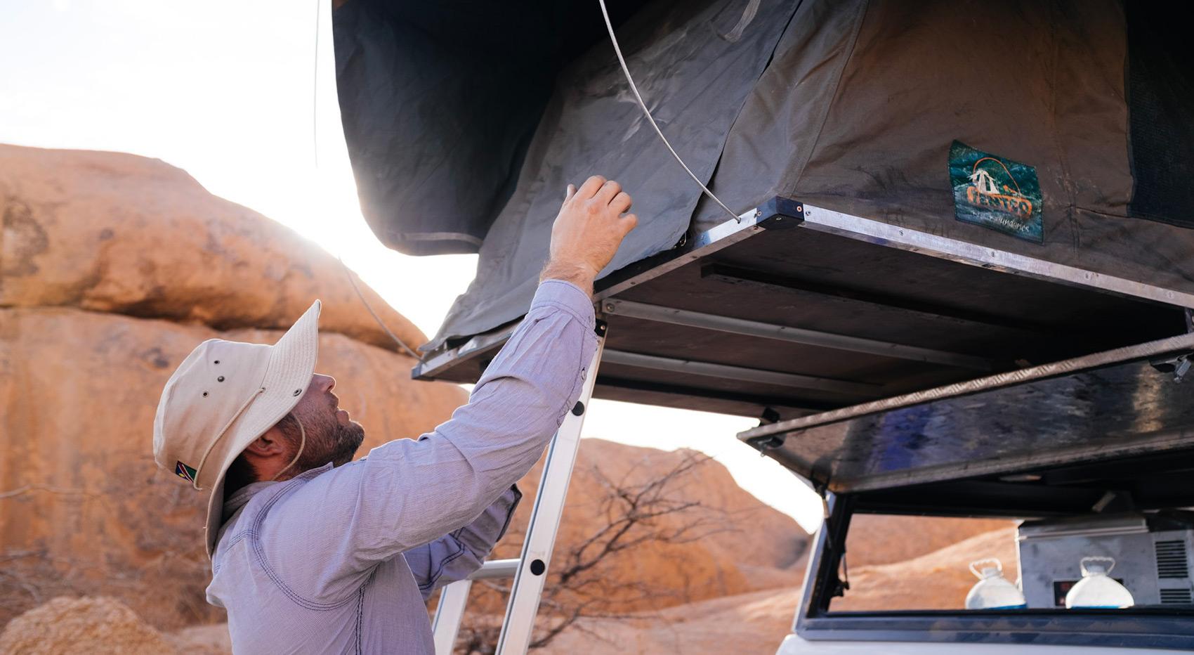 A tourist setting up his roof tent - ideal for a Namibia camping safari. A tourist setting up his roof tent - ideal for a Namibia camping safari.